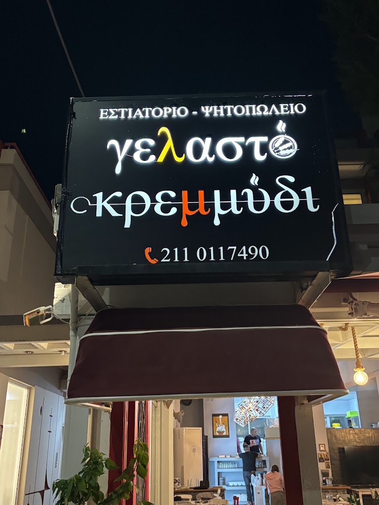 Nighttime entrance with the illuminated Gelasto Kremmydi sign
